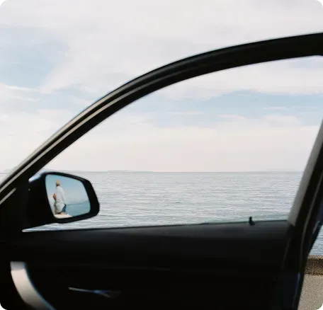 a vehicle door open to show a body of water in the background